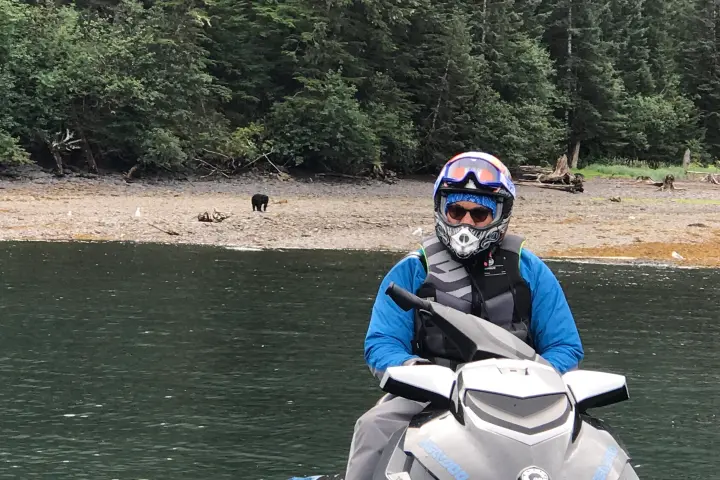 a man riding a motorcycle next to a body of water